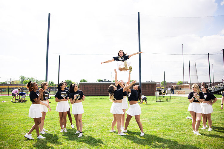 A cheerleader falls back into her group after being thrown up in the air.