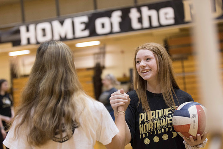 Two students shake hands during a volleyball intramural