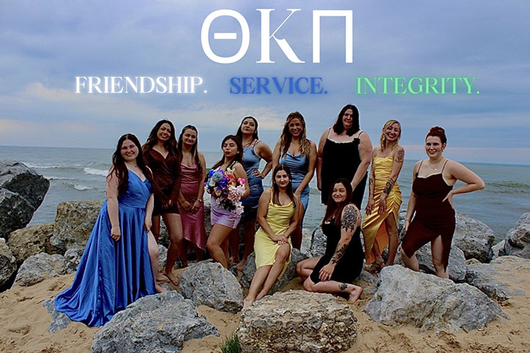 Theta Kappa Pi members pose on the beach. Text on top of the photo reads "Theta Kappa Pi; Friendship. Service. Integrity"