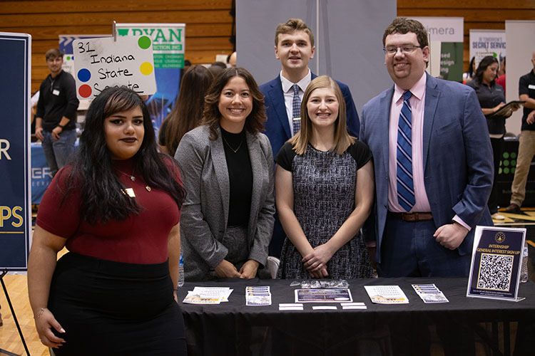 Five individuals stand at a table during a career fair at Purdue University Northwest.