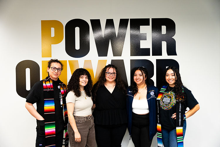 Five PNW students together for photo. Two are wearing honorary Latino graduation stoles.