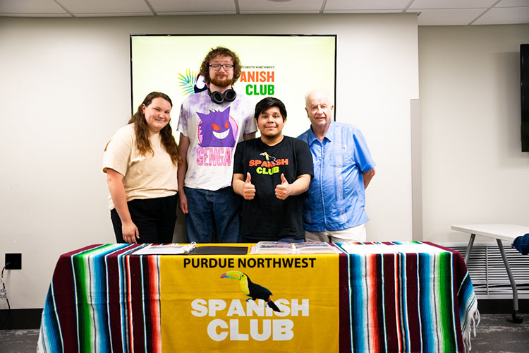 Students and a professor gather at a table for the Spanish club.