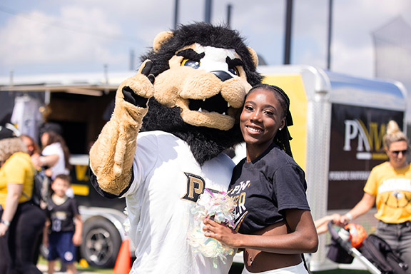 A cheerleader poses with PNW mascot Leo.