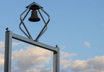 The top of PNW's Bell Tower with a cloudy blue sky in the background.