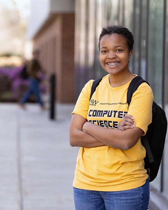A PNW student stands outdoors in a Computer Science t-shirt