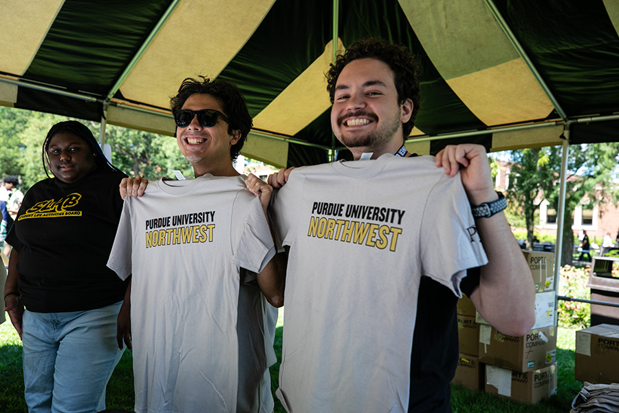 Fall 2025 Welcome Rally, two students holding up the welcome week t-shirts