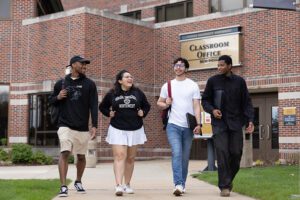 Four PNW students walk together outside of the Classroom Office Building.
