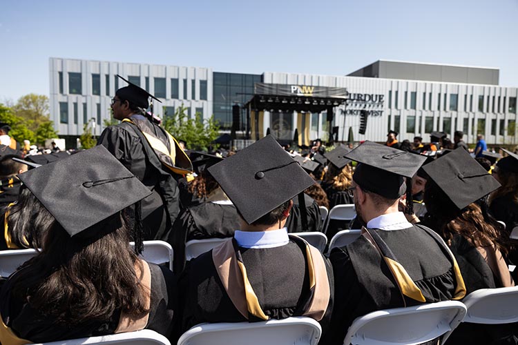 PNW graduates sit together outdoors at Commencement