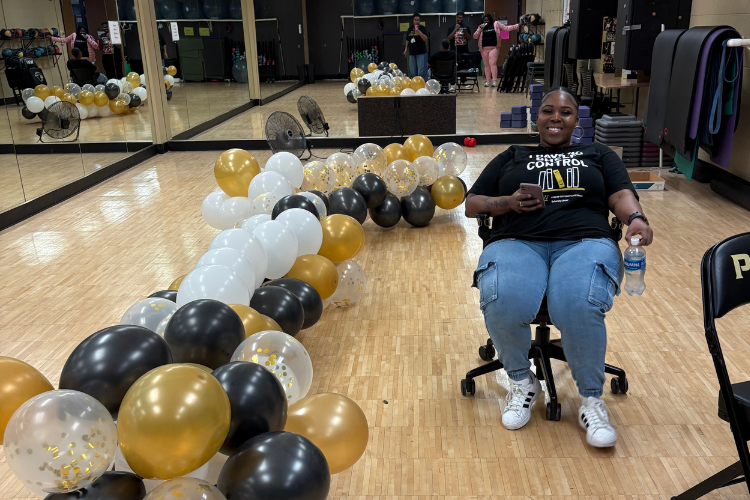 Student sitting down with balloons on floor
