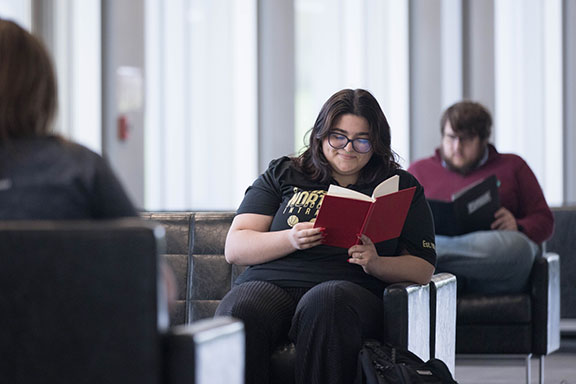 A student sits on the PNW Westville campus and reads a book.