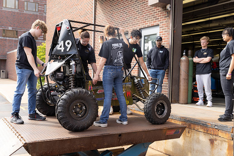 Students pose around a baja car.