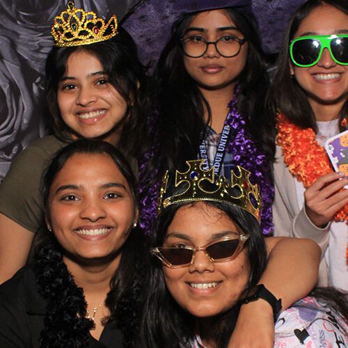 Six students pose together in a Halloween photo booth