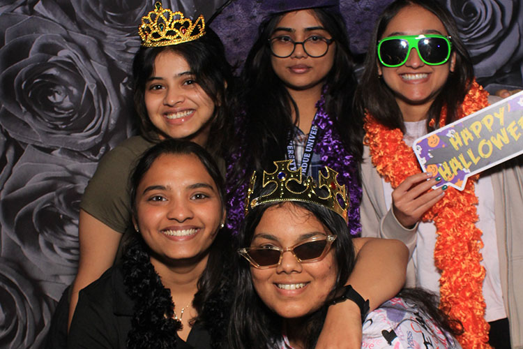 Six students pose together in a Halloween photo booth