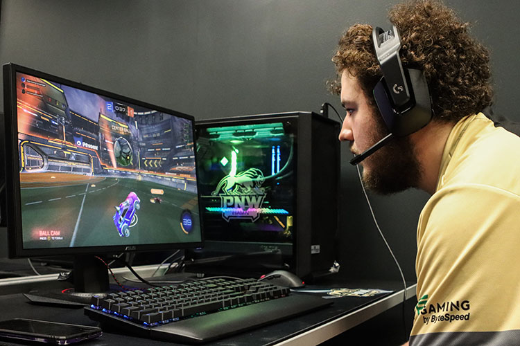 A student sits at a gaming pc playing a racing game.