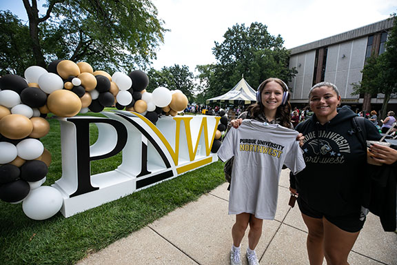 Students pose in front of a PNW monogram statue during a welcome rally.