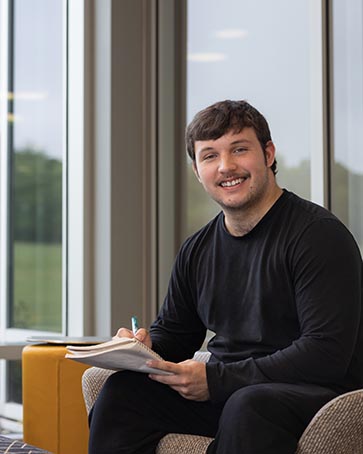 A PNW student sits in a campus lounge.