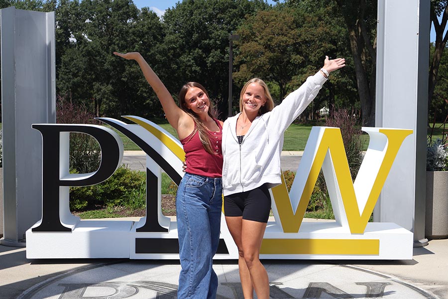 Two students posing in front of the PNW sign on the first day of school