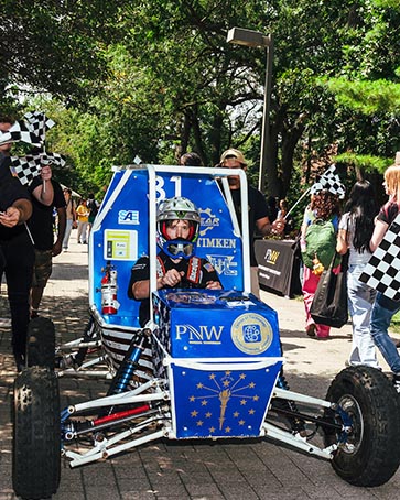 A student drives a race car at the Welcome Rally.