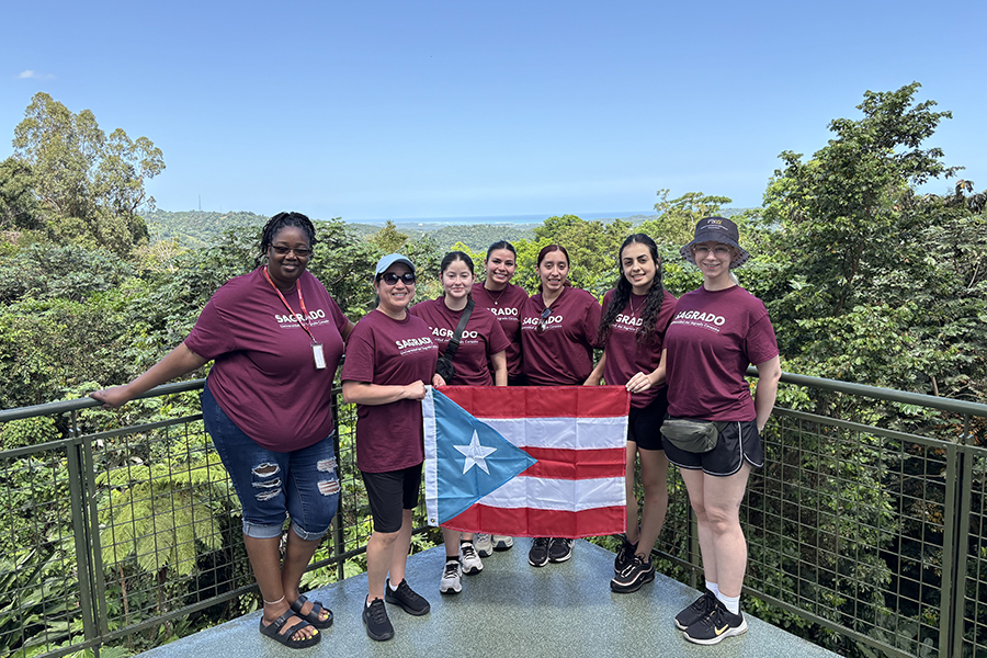 Study Away in Puerto Rico - 7 CON students holding a PR flag in front of trees