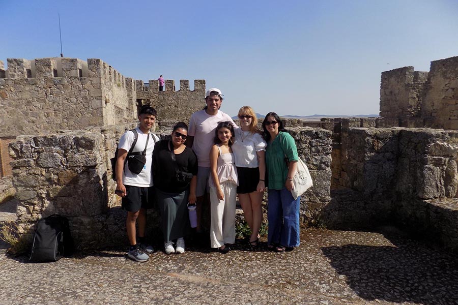 A group of PNW students standing in front of a rocky wall in Spain for the Study Away Summer program.