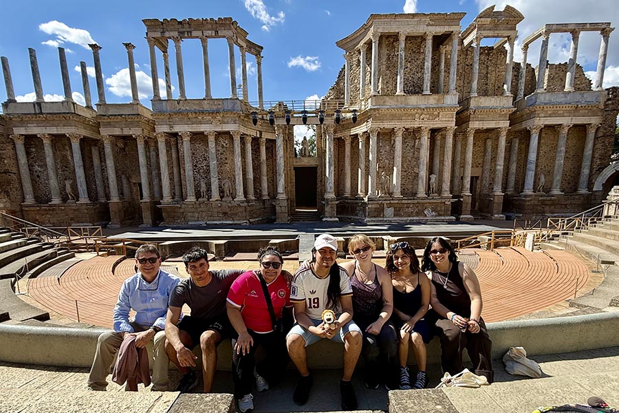 A group of PNW students sitting in front of a structure in Spain for the Study Away Summer program.