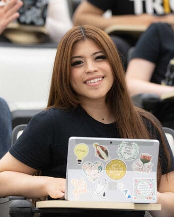 A student in a classroom with a laptop