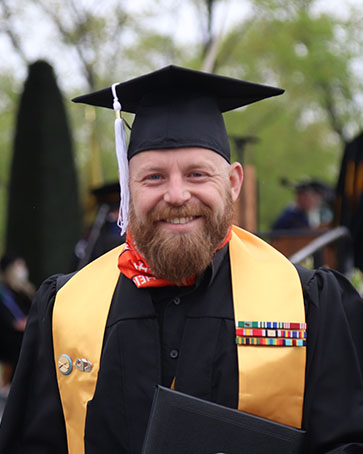 A veteran poses with their degree holder at commencement