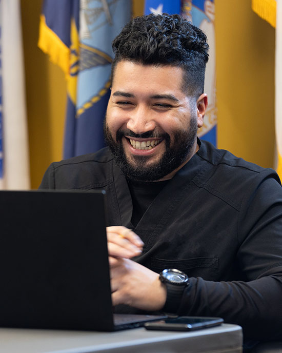 A student veteran sits at a laptop in the Veterans Services lounge