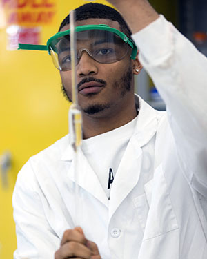 A student in a lab coat does a measurement