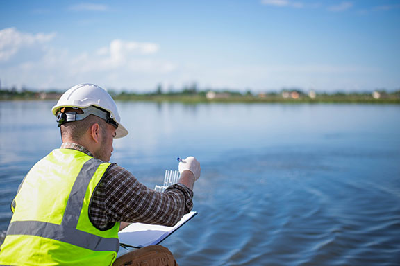 A specialist engineer at a treatment pond is checking the water quality of the treated pond.