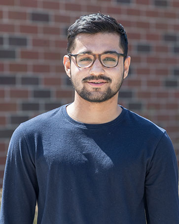 A student smiles while standing outside