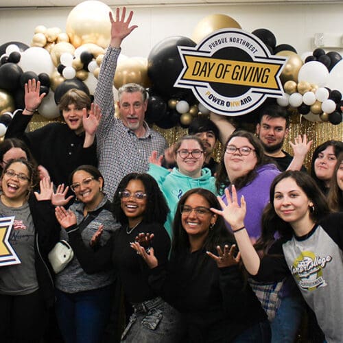 A group of people smiling and posing with colorful balloons at Purdue Northwest Day of Giving.