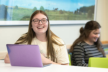 A PNW student laughs behind a computer