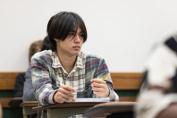 A PNW student takes notes in the classroom