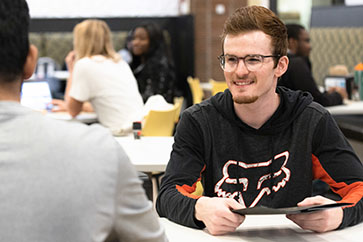 A PNW student holds a menu in a dining hall