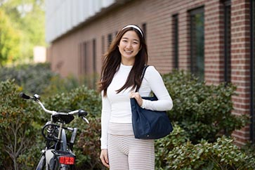 PNW student posing outside on campus while holding a bag 363x242