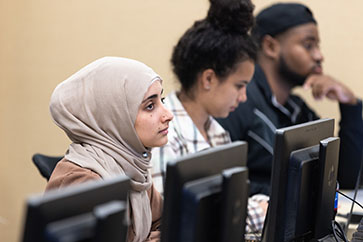 A student in a head scarf listens in a computer classroom