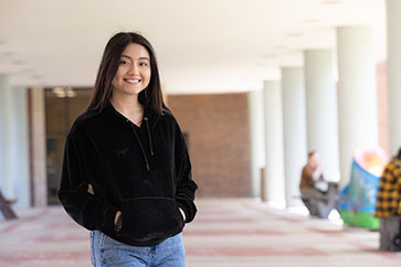 A PNW student by the Student Union and Library Building