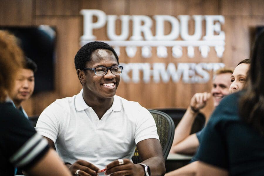 student sitting in front of PNW sign