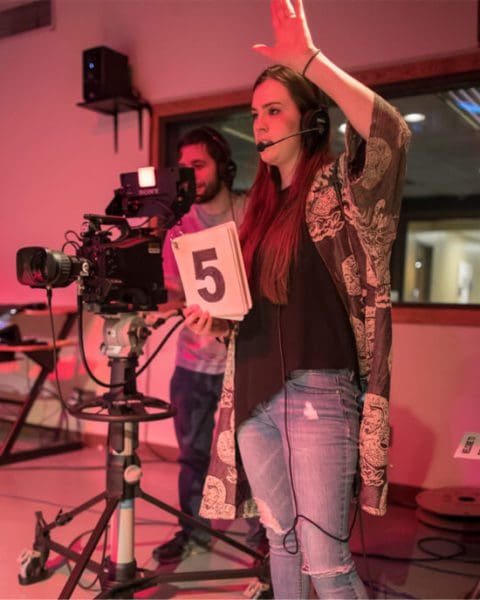 two students behind camera holding 5 sign