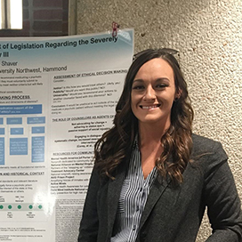 Angelicah Shaver stands in front of a poster