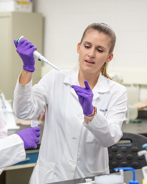 Professor Lindsey Gielda works with students in a lab.