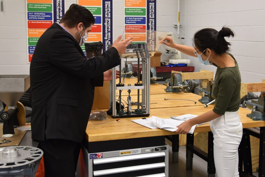 Afshin Zahraee, assistant professor, Mechanical Engineering Technology (left) and Ran Zhou, assistant professor of Mechanical Engineering examine a miniature tensile testing machine for 3D printed parts and specimen for potential use in Remote Knowledge Labs.
