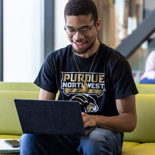 Student sits on a couch while looking at a laptop