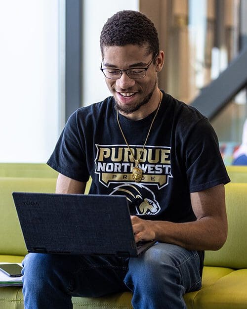 Student sits on a couch while looking at a laptop