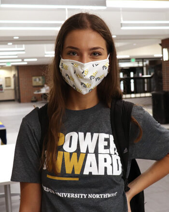 A student wears a PNW mask and Power Onward shirt in PNW's Student Union and Library Building.