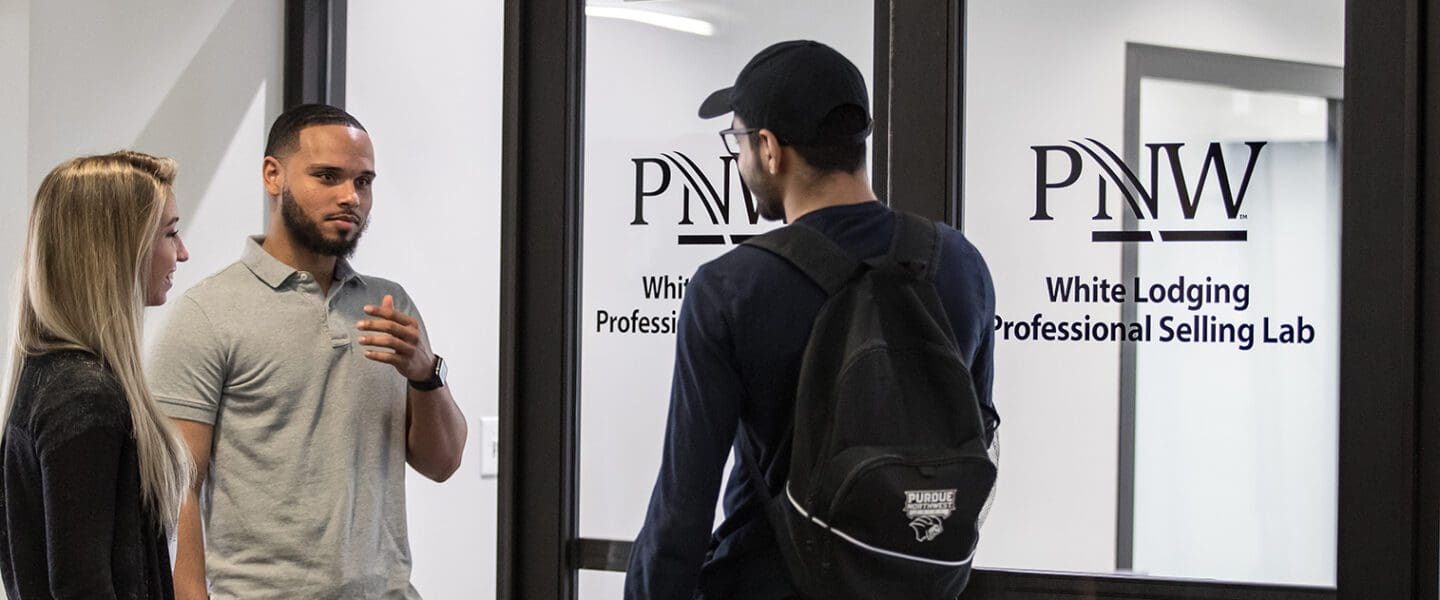 Three students standing outside of the Selling lab
