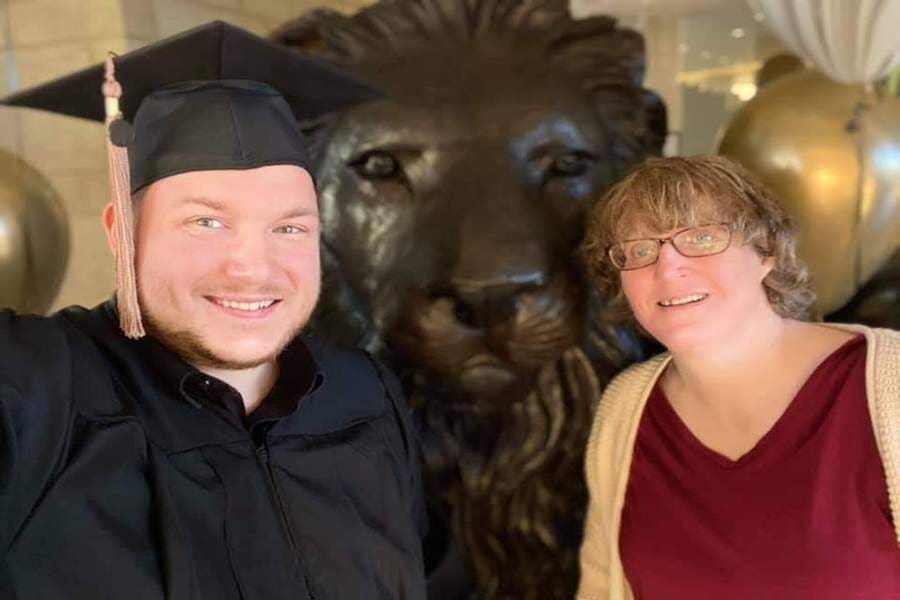 PNW Graduate Timothy Paul poses with a PNW lion and a family member.