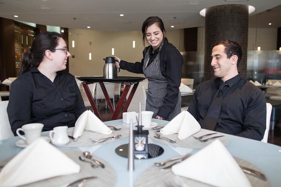 A student serves a table in the PNW Restaurant