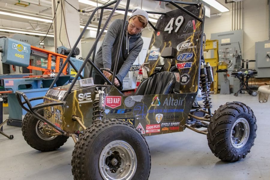 A student poses next to a buggy